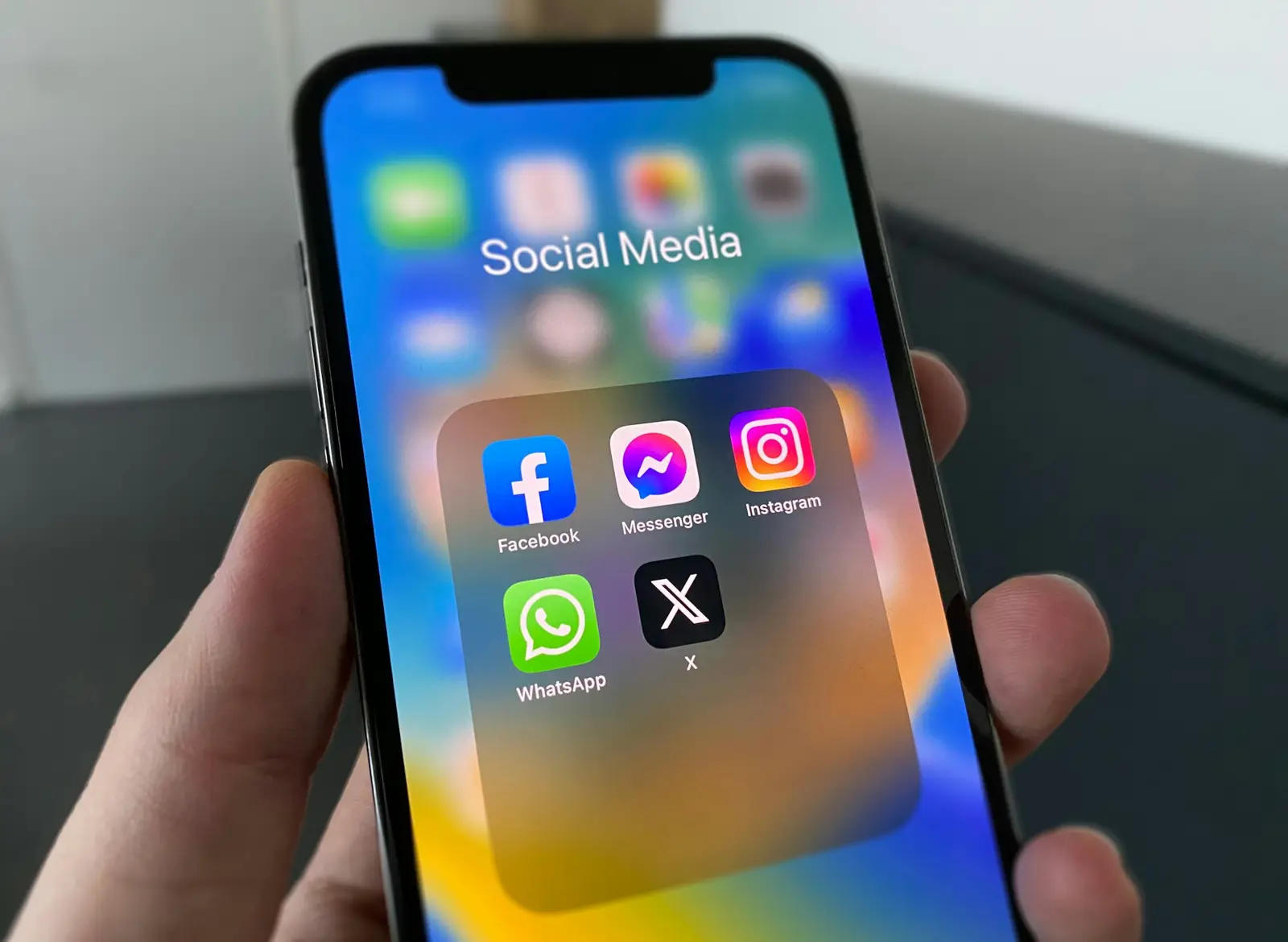 Mano sosteniendo un celular con las aplicaciones de Facebook, Instagram, WhatsApp y X